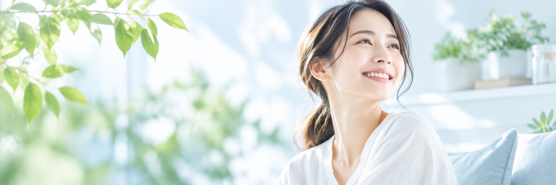明るい光と観葉植物に囲まれてほほえむ人
